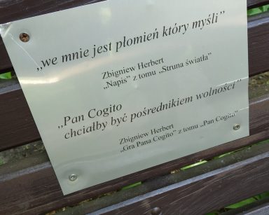Ławka Pana Cogito w Sopocie z przytwierdzoną tabliczką. Na tabliczce cytaty z dzieł Zbigniewa Herberta.