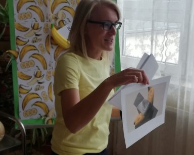 Kierowniczka Ilona Gajewska pokazuje zdjęcie pracy Cattelana. To banan przyklejony do ściany srebrną taśmą.
