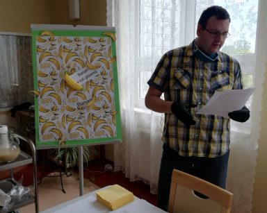 Administrator Łukasz Cielebański czyta ciekawostki o bananach. W tle plakat w żółte banany na białym tle.
