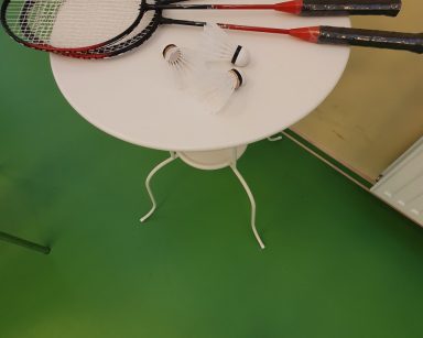 Biały stolik. Na blacie rakiety i lotki do gry w badmintona.