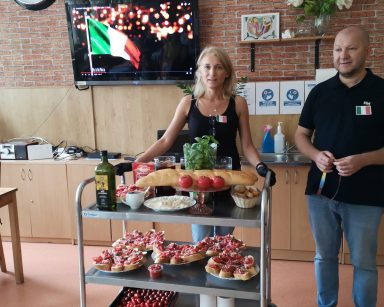 Kierownicy Ilona Gajewska i Arkadiusz Wanat przy wózku. Na wózku talerze z kanapkami, pomidory, mozzarella, oliwa, bazylia.