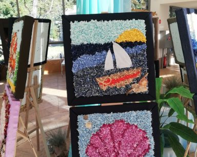 Ogród zimowy. Na sztalugach obrazy o tematyce morskiej wykonane z tkanin. Nad nimi dekoracja, kolorowe rybki z materiału.
