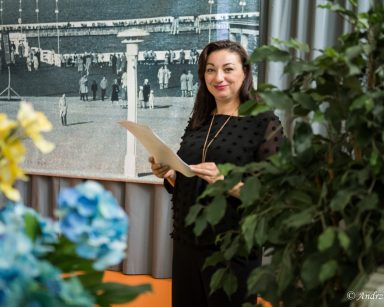Terapeutka Małgorzata Jancelewicz stoi na tle biało-czarnego plakatu przedstawiającego molo w Sopocie. Uśmiecha się.
