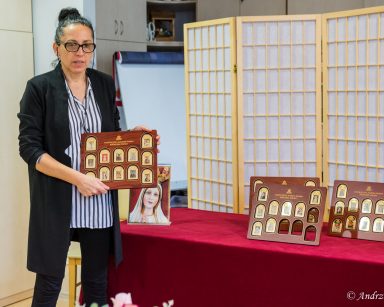 Sala. Terapeutka Magdalena Poraj-Górska pokazuje tablice z kolekcją obrazów Matki Boskiej na małych złotych sztabkach.