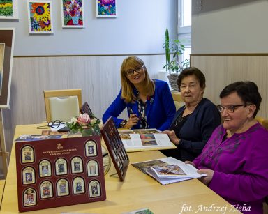 Dyrektor Agnieszka Cysewska, dwie seniorki przy stole. Uśmiechają się. Na stole portrety Matki Boskiej.