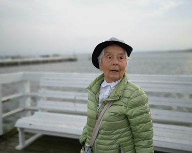 Molo w Sopocie. Seniorka na spacerze. Ma ciepła kurtkę i kapelusz.