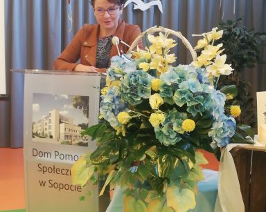Sala. Wiceprezydentka Magdalena Czarzyńska-Jachim przy mównicy. Obok dekoracja: na skrzynkach kwiaty, sieć rybacka, świece.