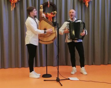 Sala. Dwaj muzycy z zespołu Galicia Folk Band w czasie występu. Grają i śpiewają.
