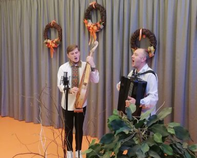 Sala. Dwaj muzycy z zespołu Galicia Folk Band w czasie występu. Grają i śpiewają.