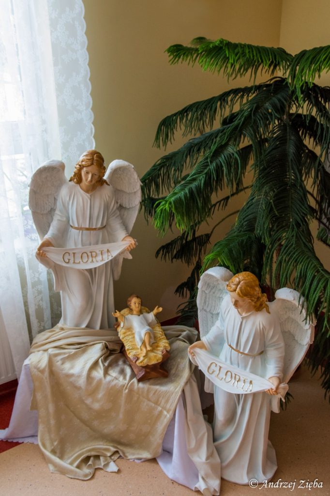 Korytarz. Dwie figurki aniołów. Mają szarfy z napisem "Gloria". Miedzy nimi figurka dzieciątka w kołysce.