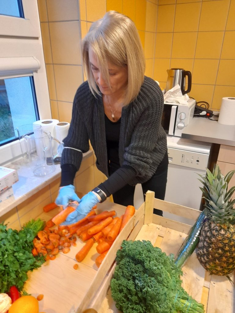 Kuchnia. Nad stołem nachyla się zastępczyni dyrektora Ilona Gajewska. Obiera marchewkę. Na blacie warzywa i owoce.