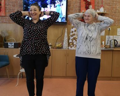 Na środku sali terapeutka Gosia Jancelewicz i seniorka. Śmieją się, pokazują figury taneczne.