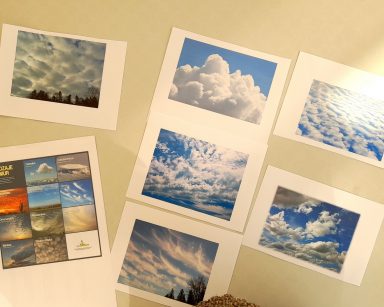 Na blacie rozłożone zdjęcia z różnymi rodzajami chmur.