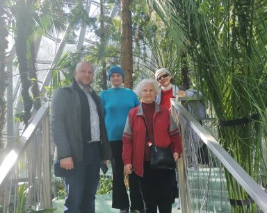 Palmiarnia w Gdańsku. Kierownik Arkadiusz Wanat i trzy seniorki pozują do zdjęcia przy egzotycznych roślinach.