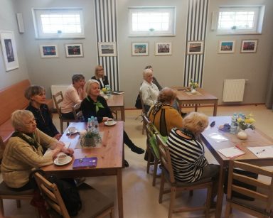 Sala. Warsztaty na temat demencji. Przy stolikach siedzą goście i dyrektor Agnieszka Cysewska.