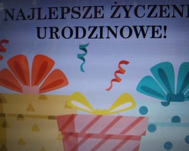 Na ekranie plakat z napisem najlepsze życzenia urodzinowe. Pod napisem rysunek trzech kolorowych prezentów.
