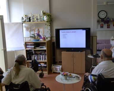 Świetlica. Terapeutka Magdalena Poraj-Górska prowadzi spotkanie. Przed nią siedzą seniorzy. Rozwiązują qiuz.