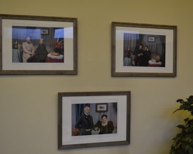 Na ścianie wiszą trzy zdjęcia. Na nich pracownicy i seniorzy w strojach z epoki romantyzmu.