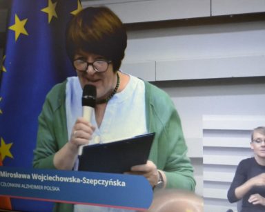 Transmisja z wystąpienia członkini Alzheimer Polska. Tłumacz języka migowego w rogu ekranu.