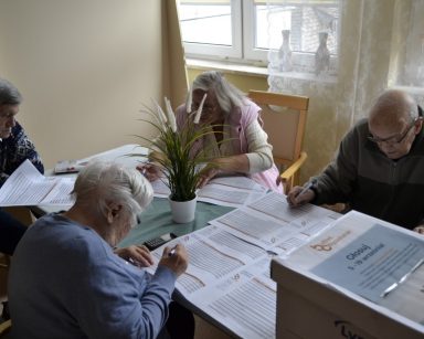 Sala. Seniorzy wypełniają karty do głosowania na Budżet Obywatelski.