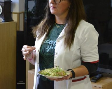 Sala. Dietetyczka Karolina Gorzkiewicz trzyma talerz z kiełkami.