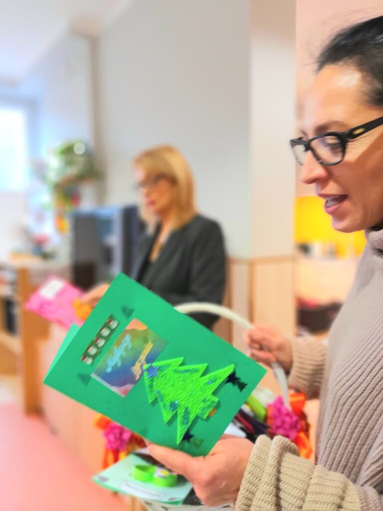 Świetlica. Na pierwszym planie terapeutka Magdalena Poraj-Górska. Trzyma zielona kartkę z choinką.