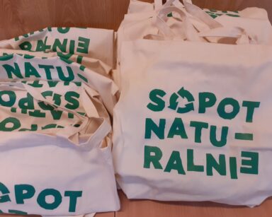 Zbliżenie. Na stole płócienne torby. Na torbach zielony napis Sopot naturalnie.