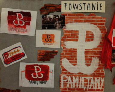Tablica z plakatami. Na plakatach napis Powstanie Warszawskie, symbole Polski Walczącej, zdjęcia powstańców.