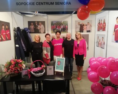 Pomieszczenie. Przedstawiciele DPS , wolontariatu i Sopockiego Centrum Seniora pozują do zdjęcia.