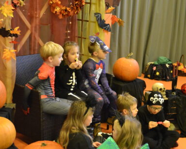 Zbliżenie. Grupa dzieci siedzi wśród ozdób Halloweenowych.