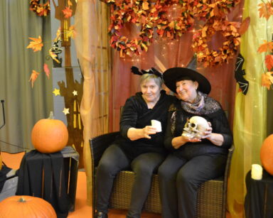 Zbliżenie. Dwie kobiety w strojach Halloween pozują do zdjęcia. Jedna trzyma świeczkę druga kobieta trzyma czaszkę.