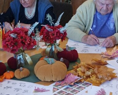 Zbliżenie. Stół. Na stole ozdobne dynie i kwiaty w wazonie oraz kolorowanka w grzyby, zdjęcia grzybów, kredki.