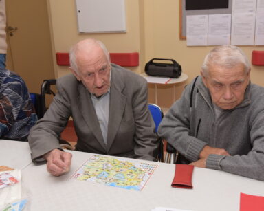 Zbliżenie. Dwóch mężczyzn siedzi przy stole. Na stole leży mapa Polski.