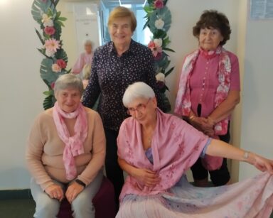 Zbliżenie. Cztery kobiety. Trzy ubrane na różowo, jedna na niebiesko pozują do zdjęcia.