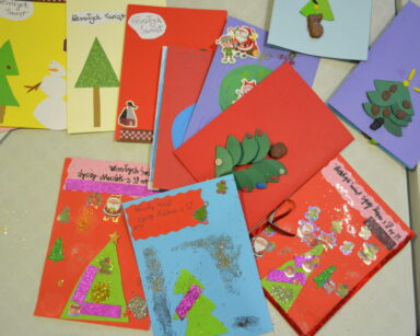Zbliżenie. Stół. Na stole wiele kolorowych świątecznych kartek przygotowanych przez dzieci.