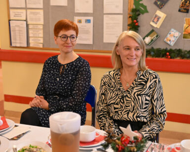Zbliżenie. Dwie kobiety siedzą przy stole wigilijnym. Na stole potrawy i ozdoby świąteczne.