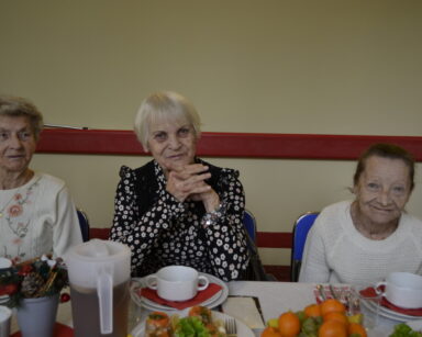 Zbliżenie. Trzy seniorki siedzą przy wigilijnym stole. Seniorki pozują do zdjęcia.