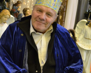 Zbliżenie. Szopka. Senior przebrany za króla. Na głowie korona, ubrany jest w niebieską szatę.