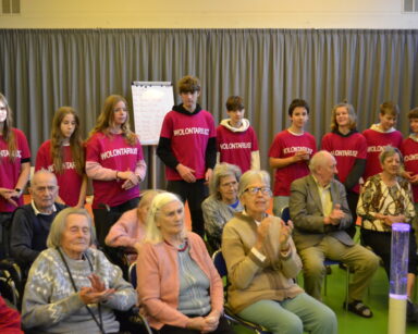 Sala. Grupa seniorów i wolontariuszy pozuje do zdjęcia.