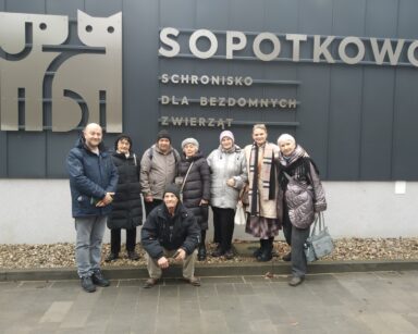 Grupa osób pozuje do zdjęcia przed schroniskiem dla zwierząt w Sopotkowie.
