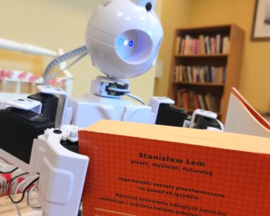 Zbliżenie. Robot JD trzyma w rączkach książkę. Stanisław Lem 