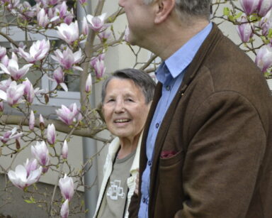 Ogród. Seniorka z mężczyzną podziwiają kwiaty drzewa magnolii.
