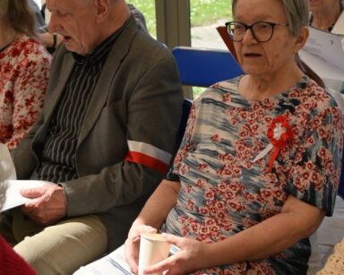 Sala. Grupa osób śpiewa, trzymając w rękach teksty polskich piosenek patriotycznych.