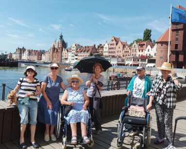 Stare miasto Gdańska. Woda, barka, drewniany podest, sześć osób pozuje do wspólnego zdjęcia.