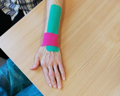 Przedramię seniorki z naklejonymi taśmami kinezjologicznymi wspomagającymi pracę mięśni