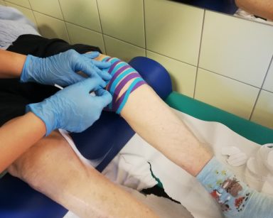 Kolano seniorki oklejone taśmami kinezjologicznymi działającymi przeciwobrzękowo