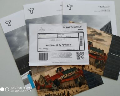 Na blacie rozłożone ulotki Gdańskiego Teatru Szekspirowskiego. Na nich bilet na musical.