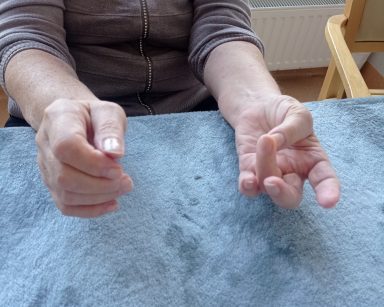 Sala. Zbliżenie na ręce starszej osoby. Wykonuje ćwiczenia dłoni.