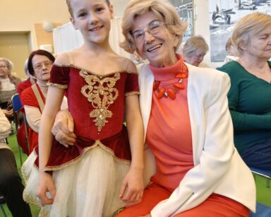 Zbliżenie. Mała baletnica i uśmiechnięta seniorka pozują do wspólnego zdjęcia.