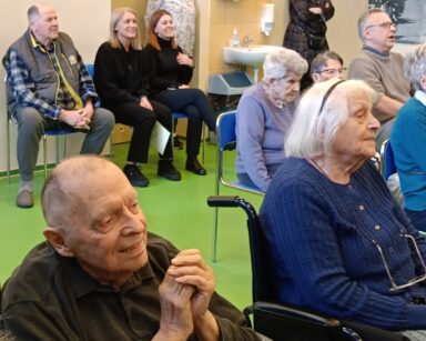 Sala. Grupa młodych osób i seniorów ogląda występ.